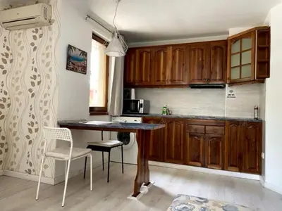 a kitchen with wooden cabinets and a table and chairs at Apart Zefira 2 Rooms in Varna City