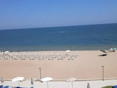 a beach with chairs and umbrellas and the ocean at Апартамент Б306 в Обзор Бийч Резорт на първа линия с перфектен изглед към плажа! in Obzor