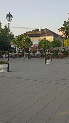 a town square with tables and benches and a building at Чудесно място с басейн 