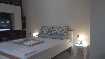 a bedroom with a white bed with a tv on it at Studio flat in the heart of Burgas in Burgas City