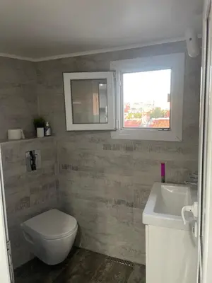 a bathroom with a toilet and a sink and a window at Studio flat in the heart of Burgas in Burgas City